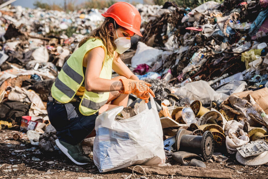 帮助清洁塑料垃圾填埋场的女志愿人员图片