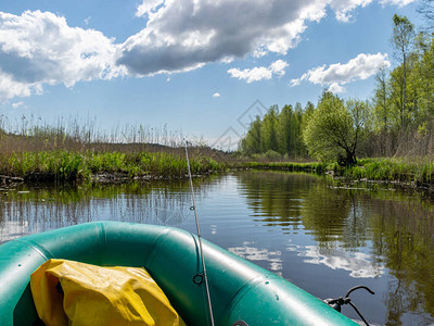 从绿渔夫的橡皮船平静河水和反光及岸上明亮绿色植被中取图片