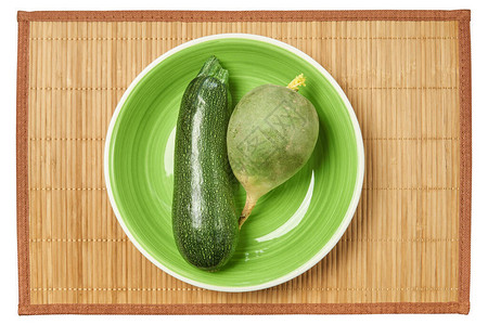 明亮的图案绿色西葫芦和淡绿色的萝卜放在甘蔗餐垫上的同一图片