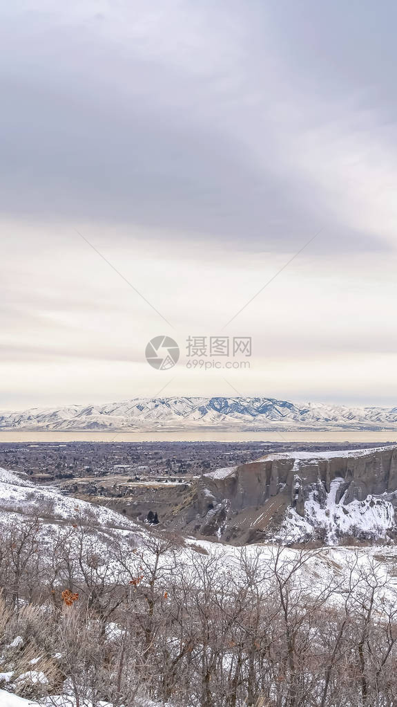 垂直的积雪山与道路在冬天多云的天空下俯瞰山谷在这冰冷的风景中还可以看到一图片