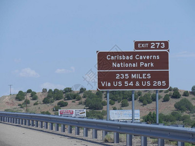 在高速公路上贴近方向标志的镜头向新墨西哥州卡尔斯巴德洞穴公园出图片