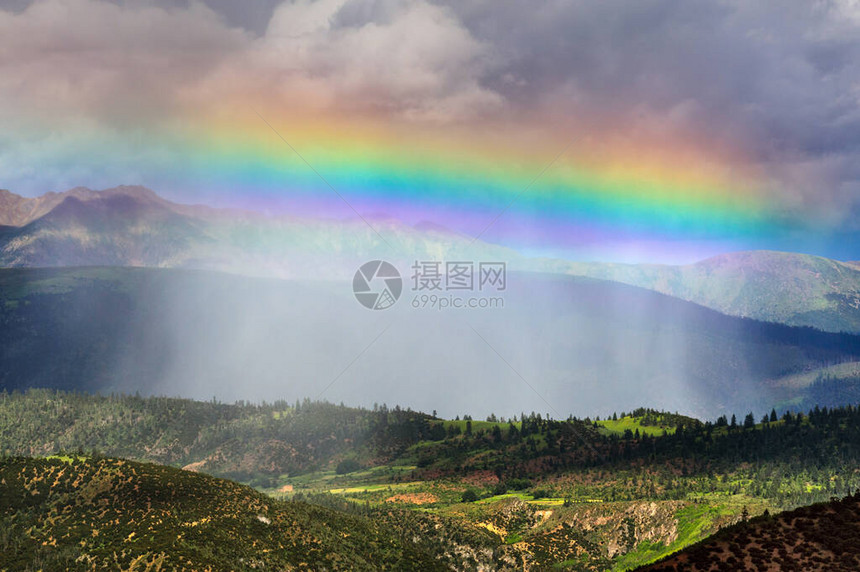 暴风雨阳光和直线彩虹笼罩在山上的一片绿山谷上图片