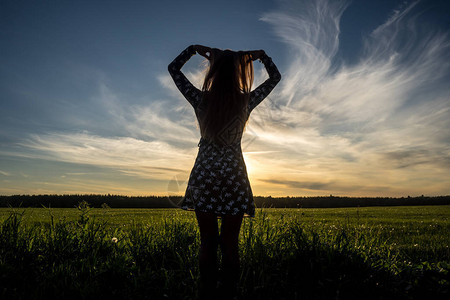 天空和绿地背景的年轻女孩的轮廓图片
