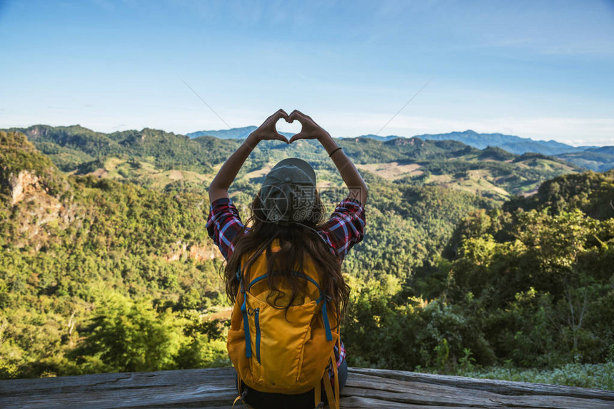 带着背包的年轻女观光客快乐旅行她举起手来做一个心脏形状享受山上自图片