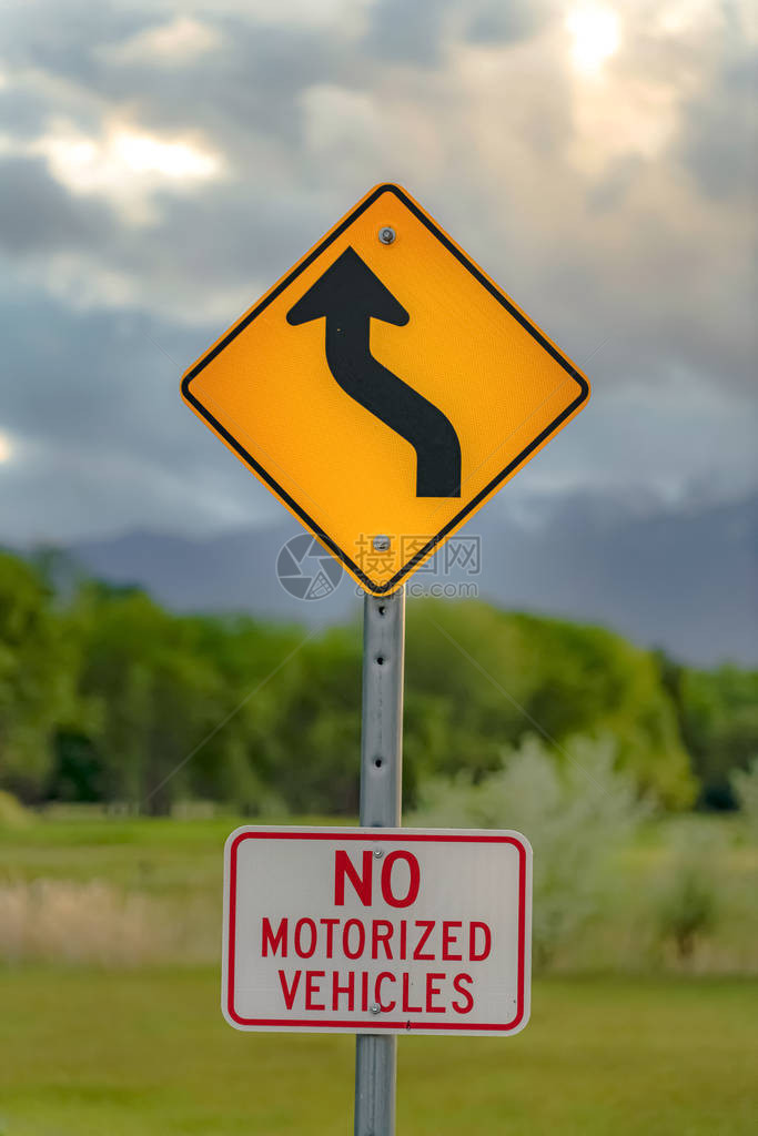 前方蜿蜒道路标志和禁止机动车辆标志的垂直特写视图图片