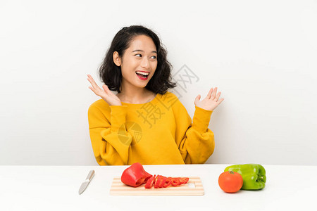 年青的亚洲女孩在一张桌子上吃蔬菜面部图片