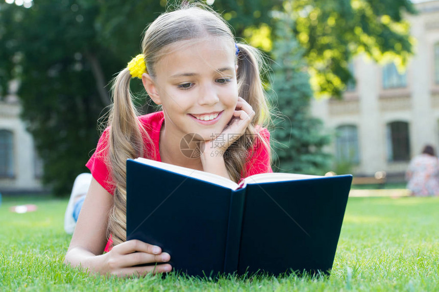 女学生一边放松绿色草坪一边读故事可爱的学生喜欢阅读上学时间适合孩子们的有趣故事愉快地学习是时候讲好故事了小图片