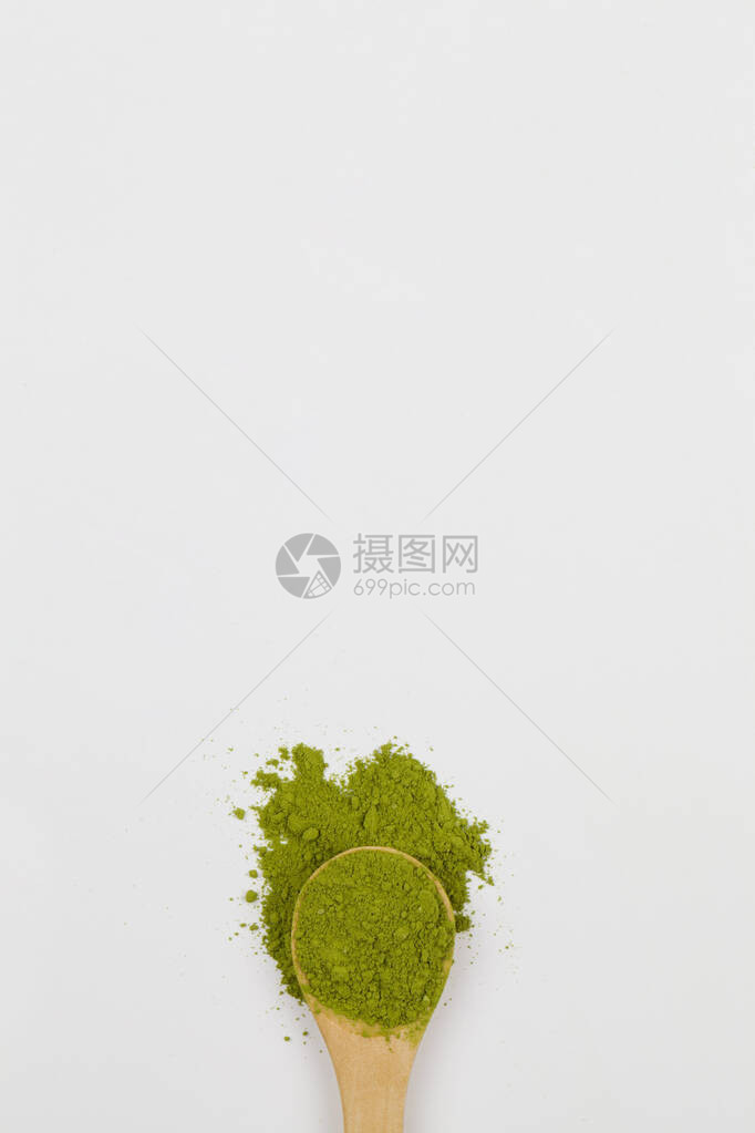 带白色背景的绿色火柴茶粉的木制勺子图片