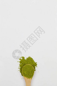 带白色背景的绿色火柴茶粉的木制勺子图片