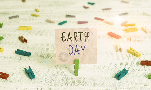显示地球日的书写笔记全球庆祝生态环境保护的商业理念绿色衣夹白木背景图片