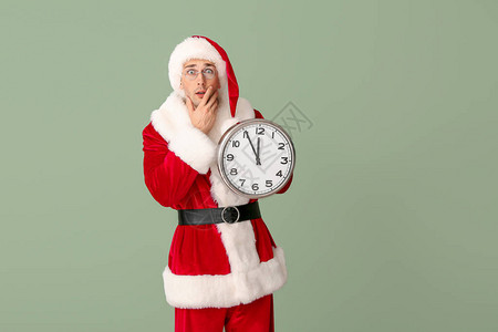 惊讶的年轻人穿着圣诞老人服装和彩色上的时钟圣诞图片