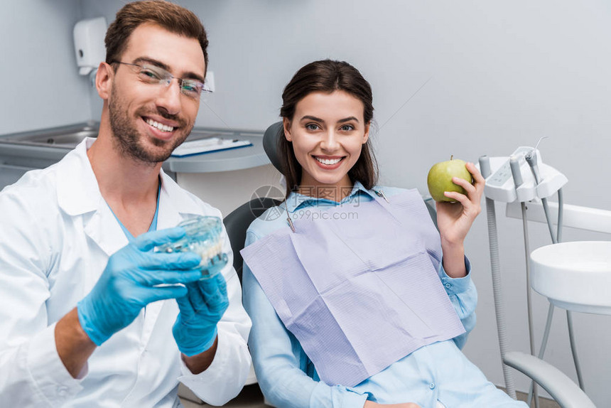 喜悦的牙医有选择重点戴眼镜拿着牙齿模样的牙齿靠近幸图片