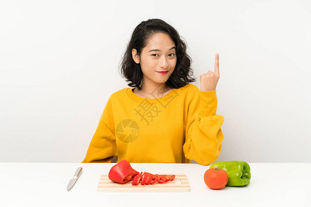 年青的有蔬菜的女孩在一张桌子上用食指着食指图片