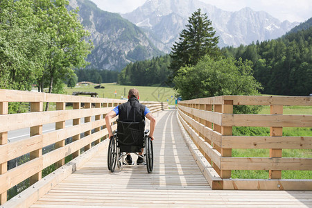 残疾青年男子在木桥上坐在轮椅上图片