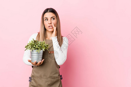 年轻的园艺女青年持有植物正在说一个秘密的热制动新闻图片