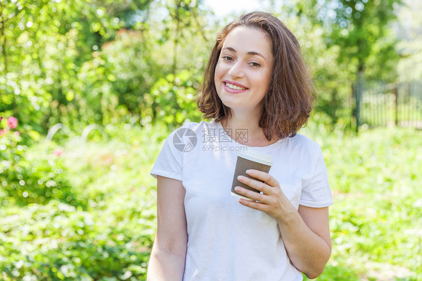 快乐的女孩微笑着在户外吃午饭美丽的年轻黑发女人带走基于公园或花园绿色背景的咖啡杯教育自由职业者图片