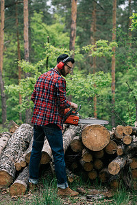 听力保护者用木链锯砍树干时的长图片
