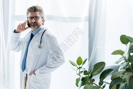 穿白大衣的英俊医生手持口袋在医图片