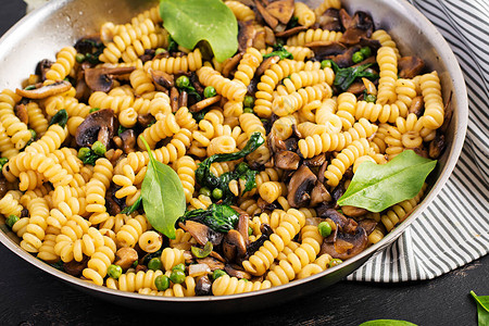 Fusilli意大利面配菠菜和蘑菇在平底锅上素食纯素食品图片