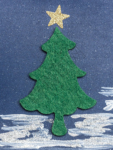 用深蓝色背景上的金色星用毛毡剪出的绿色圣诞树图片