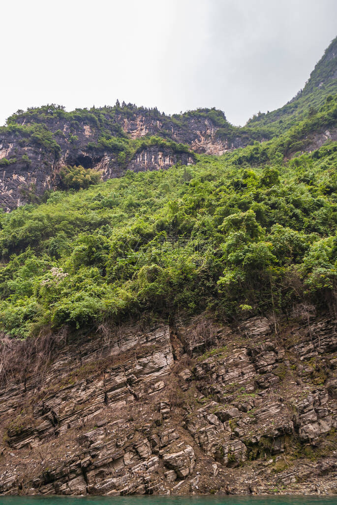 大宁河上的迷你三峡黑色洞穴高耸立在银色天空下的棕黑色悬崖上图片
