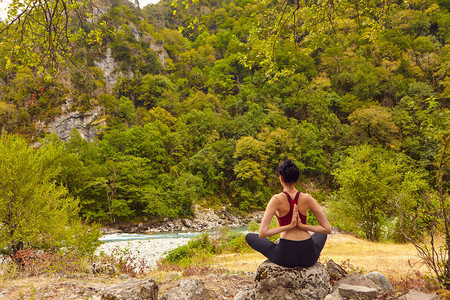 大自然中的瑜伽课独自参加运动的概念社会排斥一个女人在岩石上做瑜伽背景图片