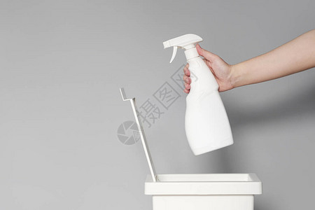 一只手将一个空的白色塑料瓶清洁产品放入回收箱图片