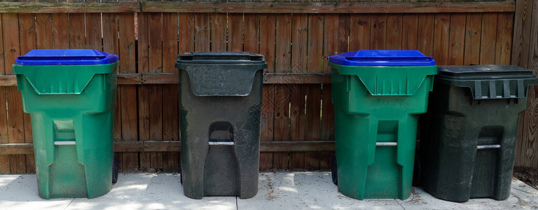 大型塑料垃圾桶站在住宅小巷的围栏图片