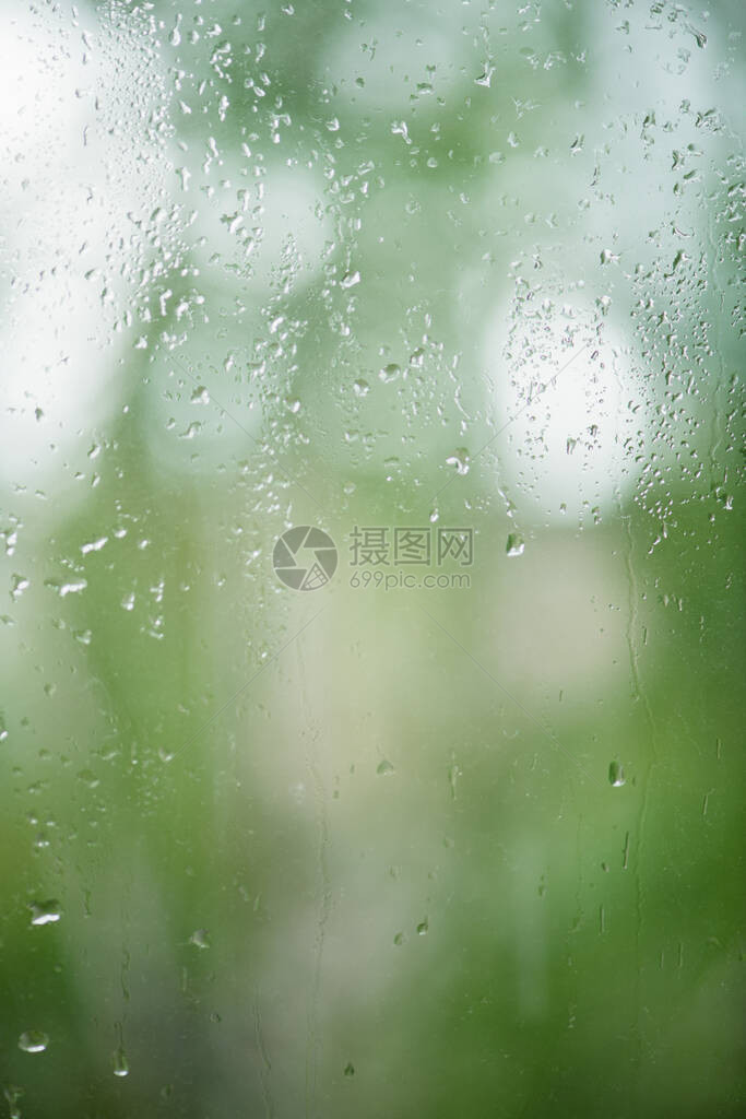 雨滴落在窗户上背景是绿树图片