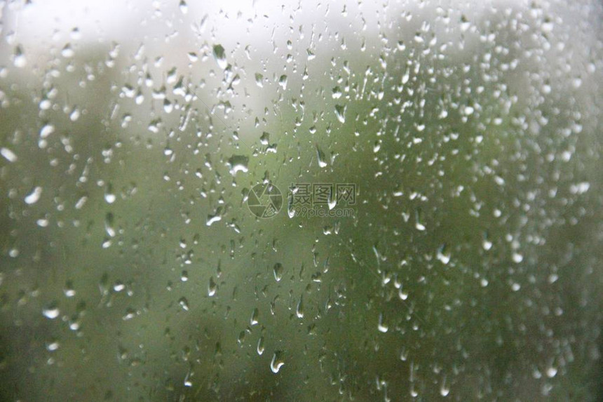 在绿色灰色城市背景下有大滴雨的窗户图片
