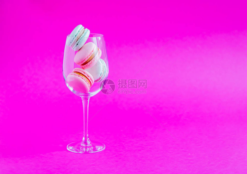 粉红色背景的玻璃杯子上的麦卡龙斯法国饼干图片