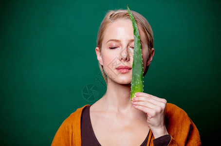 女人手里握着aloe在绿色背景的脸上图片