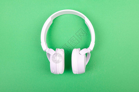 绿色背景上的无线白色耳机音乐概念在绿图片