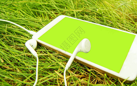 绿色草地上的耳机和白色手机图片