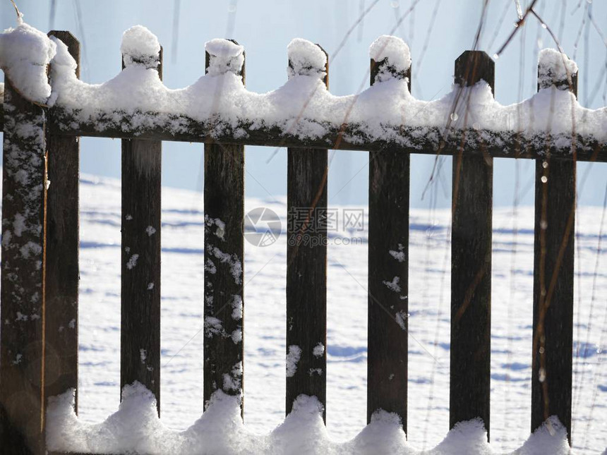 关闭顶部和底部覆盖着新鲜雪的木栅栏图片