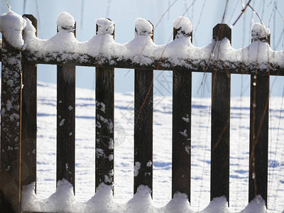 关闭顶部和底部覆盖着新鲜雪的木栅栏图片