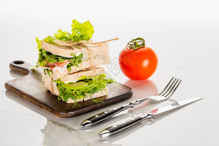 餐具附近木切板上的新鲜绿色三明治和白大理石图片