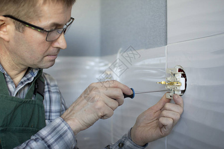 电工用螺丝起子把插座固定在墙图片