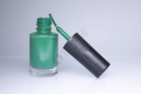 一瓶白色背景上溢出的绿色指甲油指甲油指甲修指甲概念隔图片