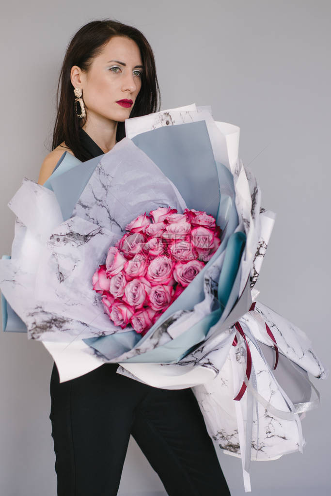 非常漂亮的花店女人拿着一束美丽的五颜六色的盛开的鲜花图片