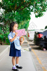 泰国校服穿泰国校服的小亚洲女孩在学校里拿着礼图片