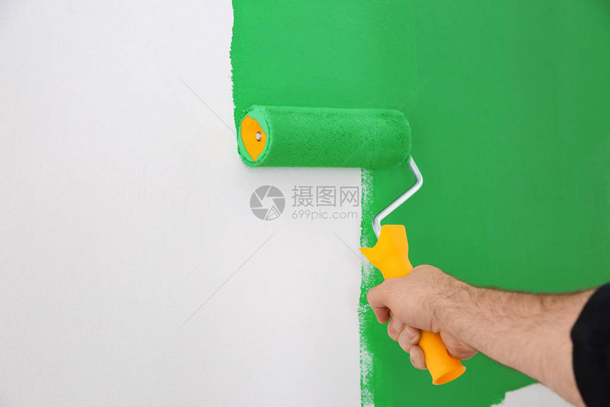 男人用绿色染料画白墙特写室内装修图片