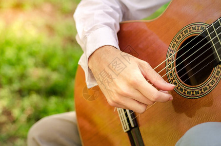 一个在公园里弹声吉他的人手在大自然中演奏音乐图片