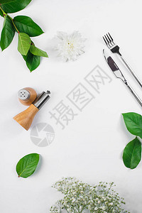 白色背景上的餐具绿叶和白花图片