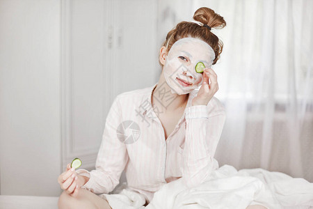 一个戴着口罩的可爱女孩用一片黄瓜遮住一只眼睛图片