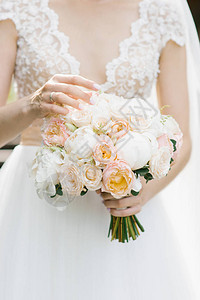 新娘用手指抚摸婚礼花束中的花朵手中握着图片