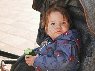 孩子吃黄瓜坐在婴儿车里情绪活跃孩图片