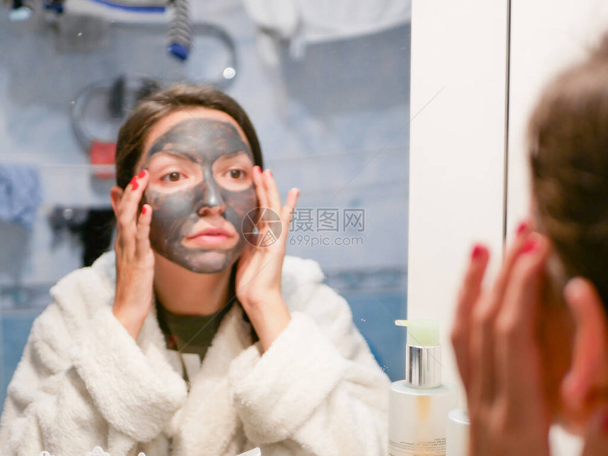 女孩和面罩她脸上戴着粘土碳黑面具的女人这个女孩照顾油皮肤美容程图片