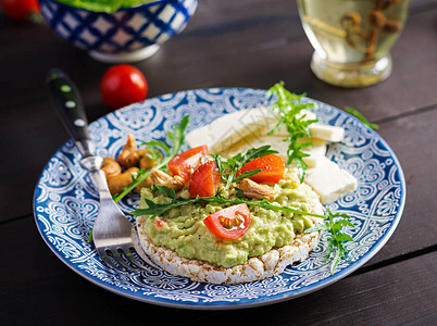 早餐或午餐的健康鳄梨吐司鳄梨芝麻菜西红柿腰果羊乳酪和胡椒图片