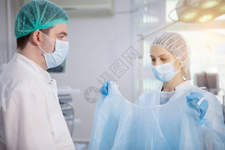 外科护士在手术室帮助医生穿上浴袍图片